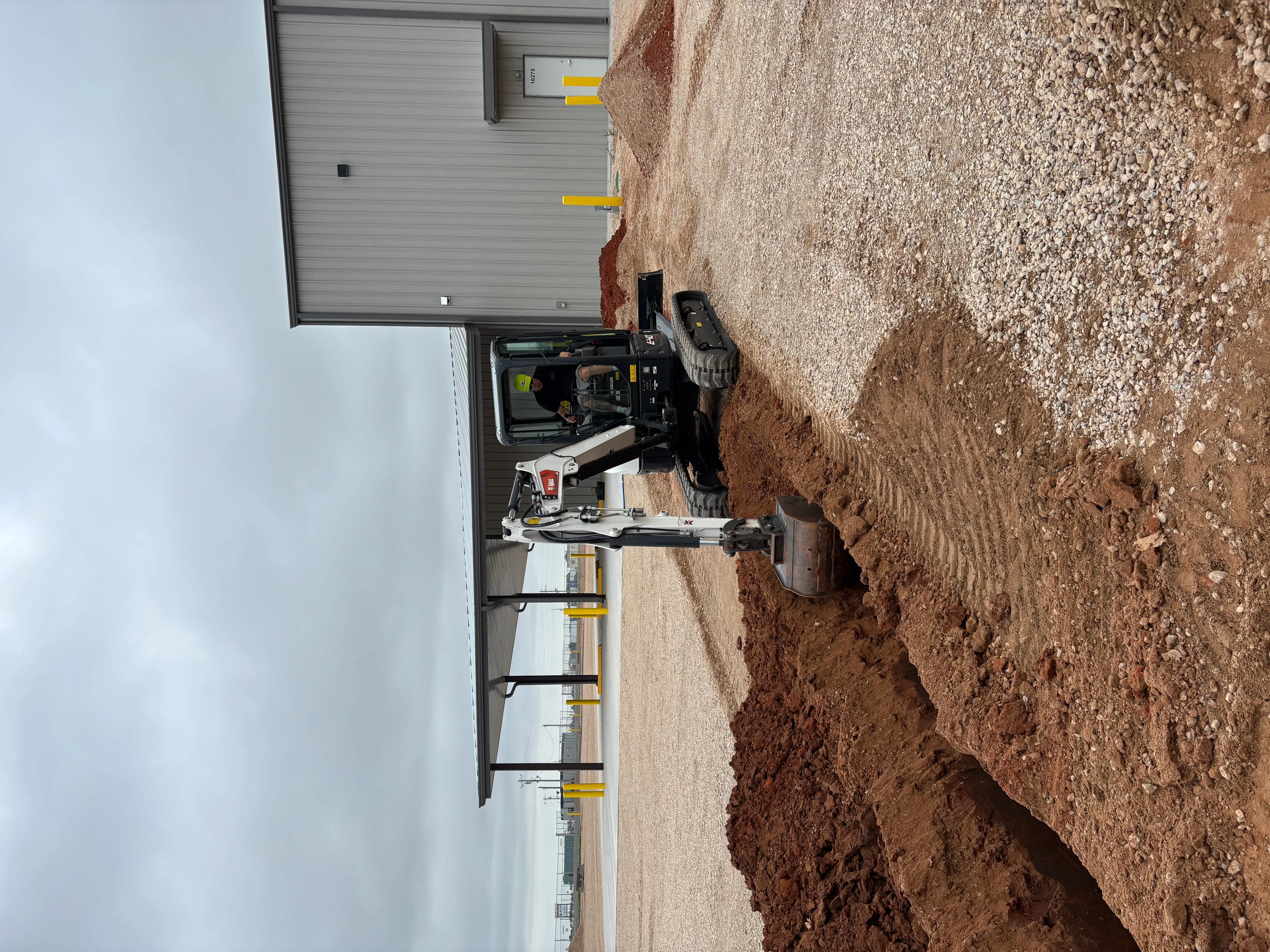 Concrete foundation pad with excavated soil base and new garage structure with metal door