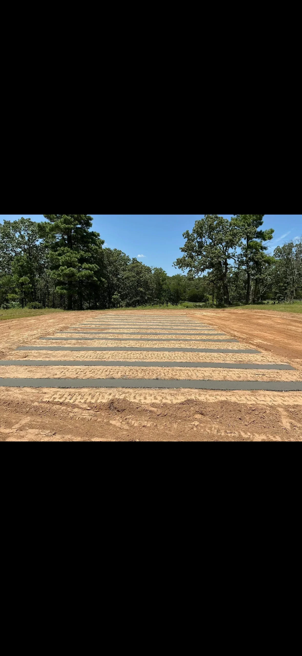 Graded driveway base with asphalt millings and compacted clay material, crowned for drainage