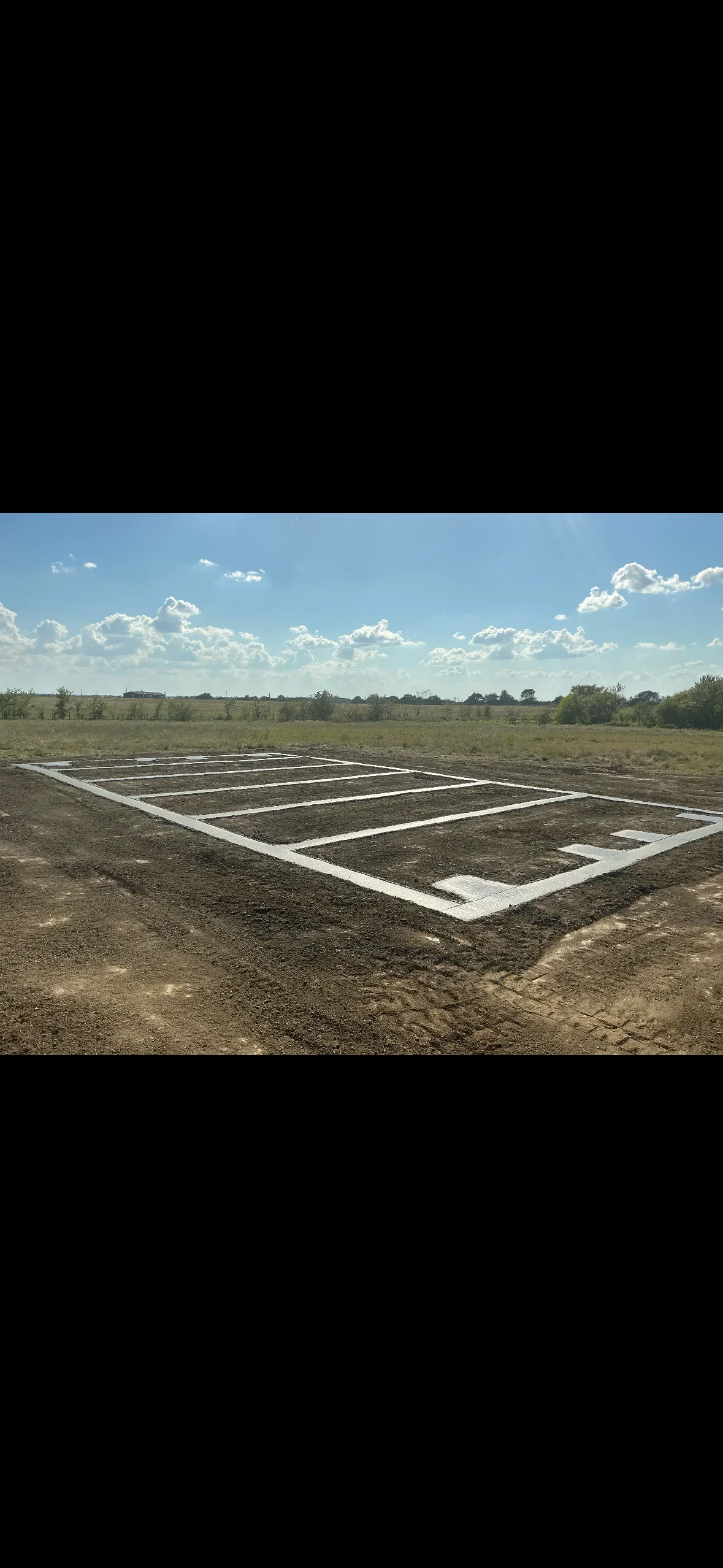White concrete footings and foundation layout lines marked on prepared soil with clear structural grid